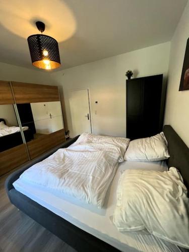 sypialnia z łóżkiem z białą pościelą i lampką w obiekcie Geräumiges Apartment am Hafen von Dortmund w Dortmundzie