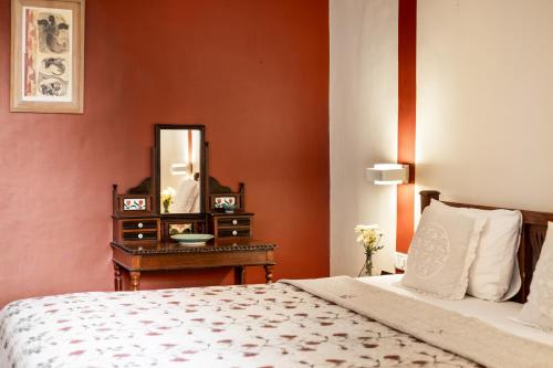 a bedroom with a bed and a dresser with a mirror at Casa Britona in Panaji
