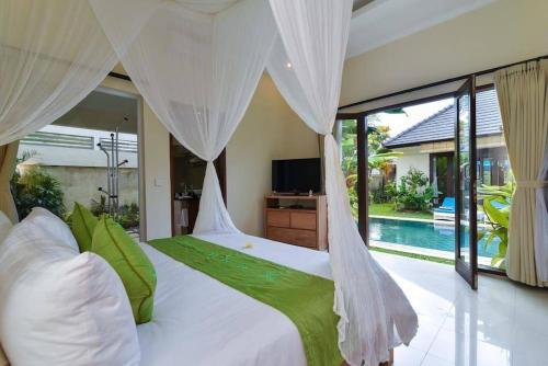 a bedroom with a white bed and a pool at Villa Intan in Legian