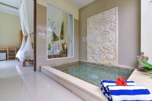 a bathroom with a plunge pool with a mirror at Villa Intan in Legian