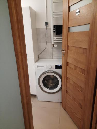 a washing machine in a small bathroom with a door at hostel52 in Gdańsk