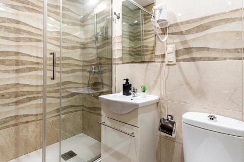een badkamer met een douche, een toilet en een wastafel bij Hostal Rincón de Sol in Madrid