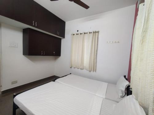 Un dormitorio pequeño con una cama blanca y una ventana. en Allamanda Abode, en Chennai