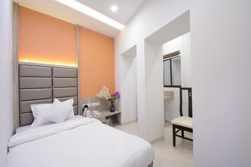a bedroom with a white bed and a chair at Hotel One Up in Ahmedabad