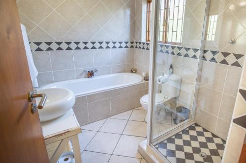 a bathroom with a tub and a toilet and a sink at Mirihof Retreat and Olive Estate in Montagu