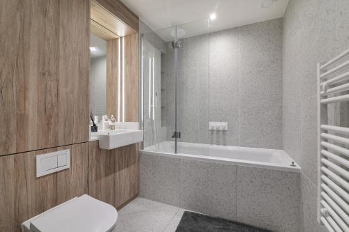 a bathroom with a tub and a toilet and a sink at Luxury Spacious Flat with Communal Gardens and Parking in London