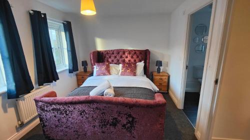 um quarto com uma cama grande e uma cadeira roxa em Graylingwell! 4/5Bedroom House Chichester Goodwood em Chichester