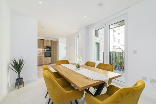 a dining room with a wooden table and yellow chairs at Luxury Spacious Flat with Communal Gardens and Parking in London