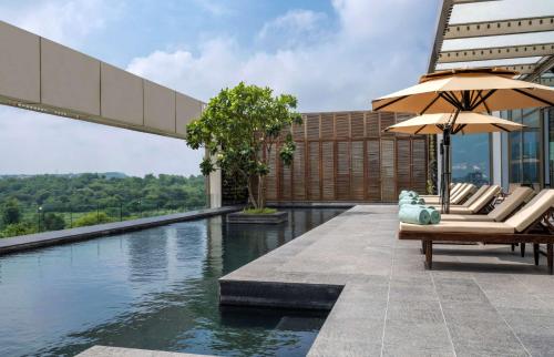 una piscina con sillas y sombrillas en un edificio en Grand Hyatt Gurgaon en Gurgaon