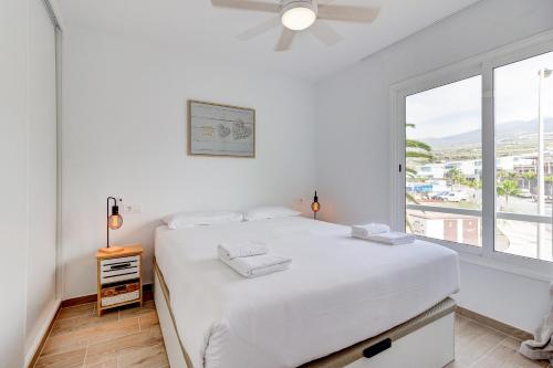 a white bedroom with a large bed and a window at The butterflies of Sueno Azul in Callao Salvaje