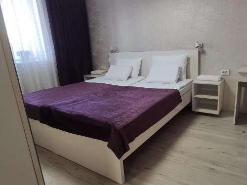 a bedroom with a large bed with a purple blanket at Apartment in the Karakol heart in Karakol