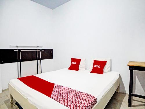a white bed with two red pillows on it at OYO 91959 La Khansa Homestay Syariah in Sunggal