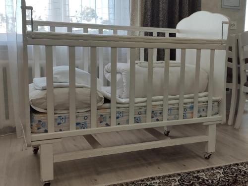 ein weißes Kinderbett mit Kissen und Decken in der Unterkunft Apartment in the Karakol heart in Karakol