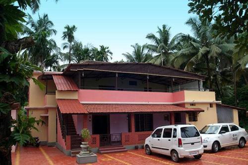 two cars parked in front of a house at Kedige Homestay in Kumta