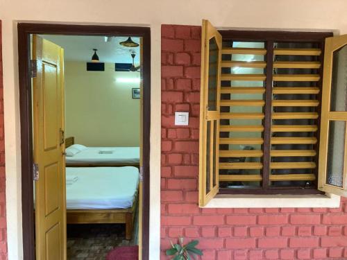 a door to a room with a bed next to a brick wall at Kedige Homestay in Kumta