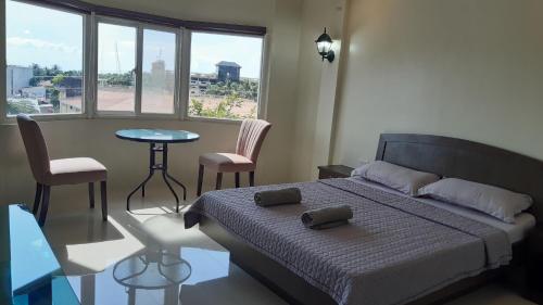 1 dormitorio con 1 cama y 1 mesa con sillas en Avana Hills Boracay Prime Panoramic Suite, en Boracay