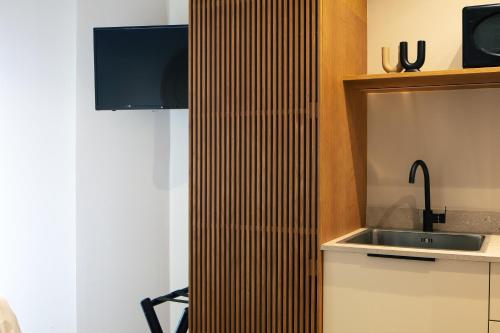 a kitchen with a sink and a wooden wall at Chapter 02 Gallery Suites - ex GD Gallery Suites in Heraklio Town