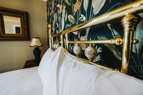 a bedroom with a bed with a gold frame at Brook Hall Hotel in Childer Thornton