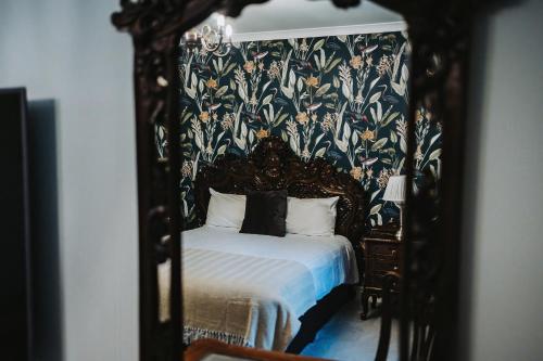 a bedroom with a canopy bed with a floral wallpaper at Brook Hall Hotel in Childer Thornton
