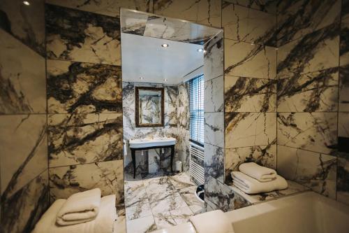 a bathroom with a mirror and a tub and a sink at Brook Hall Hotel in Childer Thornton