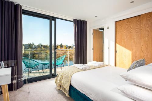 a bedroom with a bed and a balcony with a view at Family friendly property in nature reserve The Hangout ML15 in Somerford Keynes