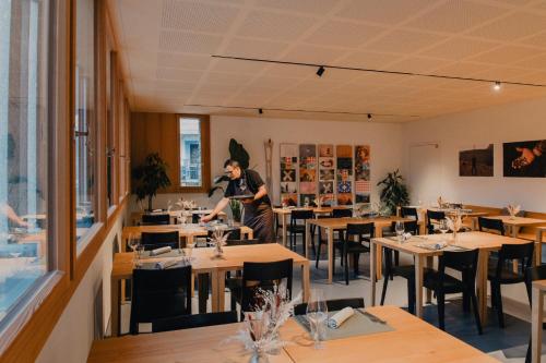 Un uomo in piedi in una sala da pranzo con tavoli di Corippo Albergo Diffuso a Corippo