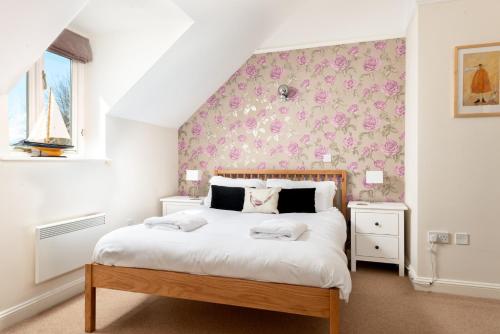 a bedroom with a large white bed with pink flowers at Family friendly property in a nature reserve The Mallards MV53 in Somerford Keynes