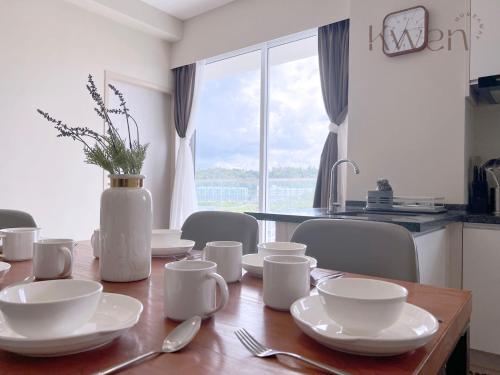a dining room table with white dishes and a vase at KWEN Suites-Tanjung Aru InfinityPool Seaview/Airport View in Kota Kinabalu