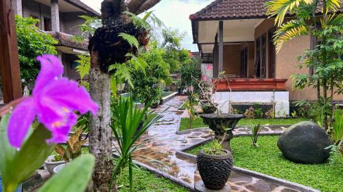 a garden with a fountain and flowers in front of a house at Gusti Home Stay Ubud in Ubud