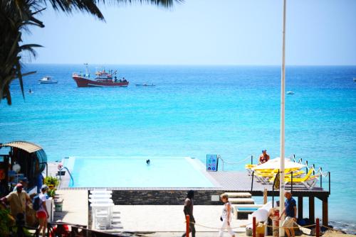 a swimming pool on the beach with a boat in the water at Hotel Odjo d'água in Santa Maria