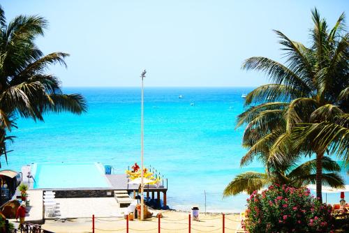 a beach with a pool and palm trees and the ocean at Hotel Odjo d'água in Santa Maria