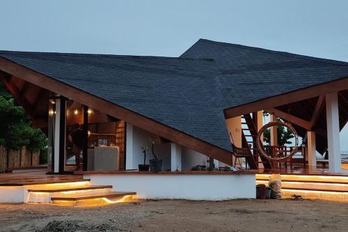 una casa con techo negro y escaleras de madera en Private beachfront villa en Roxas