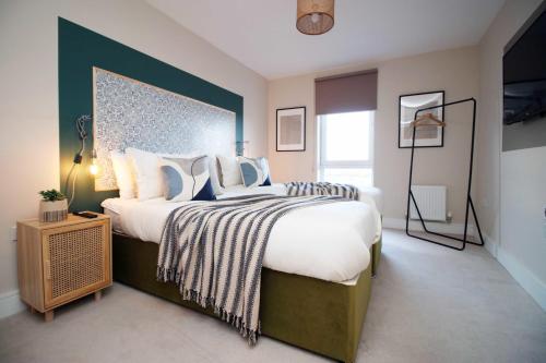 a bedroom with a large bed with a blue wall at Stylish modern retreat overlooking Poole Quay in Poole