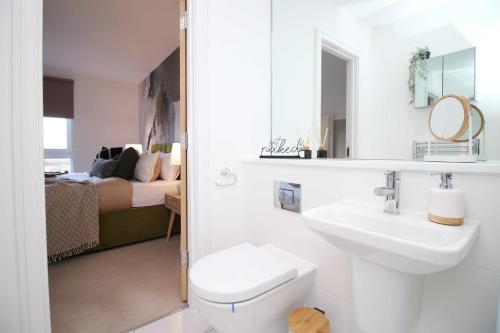a bathroom with a sink and a toilet and a bed at Stylish modern retreat overlooking Poole Quay in Poole