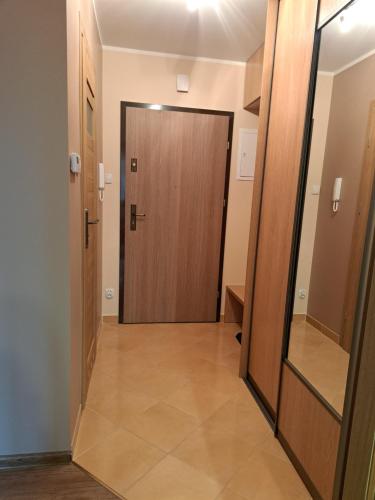 einen Flur mit Holztür und Spiegel in der Unterkunft Apartament Karmelowy in Karpacz