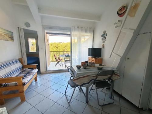 a living room with a table and chairs and a couch at Appartement T2 Cabine, mezzanine Saint Pierre la mer 4oliv41 in Saint Pierre La Mer