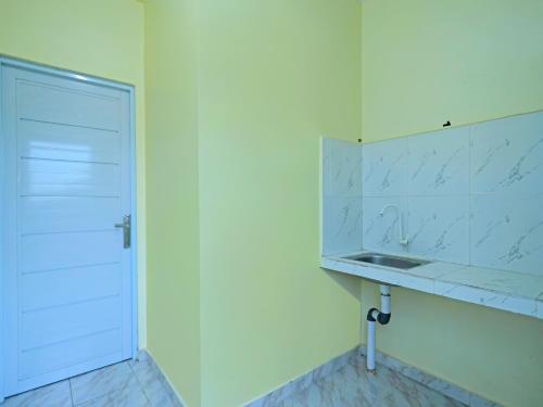 a white bathroom with a sink and a door at OYO 91974 Alfisal Syariah in Bagam