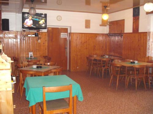 a restaurant with wooden tables and a tv on the wall at Hostinec U Valentů in Červená Voda