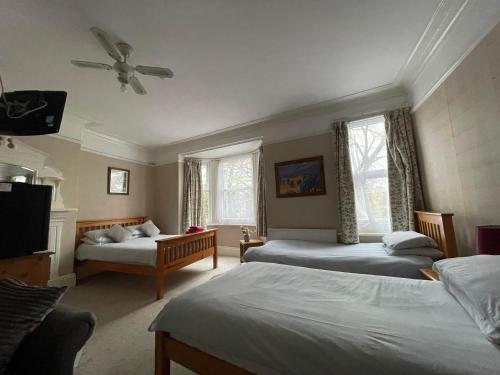 a bedroom with two beds and a ceiling fan at Burton Villa Guest House in York