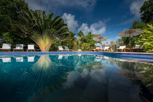 a pool at a resort with chairs and umbrellas at Pousada Mangabeiras in Ilha de Boipeba
