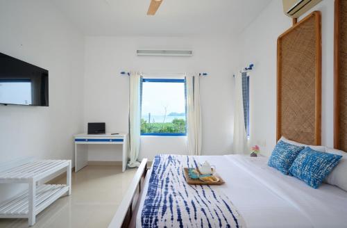 a white bedroom with a bed and a window at Seclude by the Lake, Alleppey in Alleppey