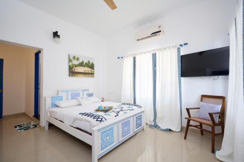 a white bedroom with a bed with blue and white sheets at Seclude by the Lake, Alleppey in Alleppey