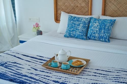 a tray with a tea pot and cookies on a bed at Seclude by the Lake, Alleppey in Alleppey