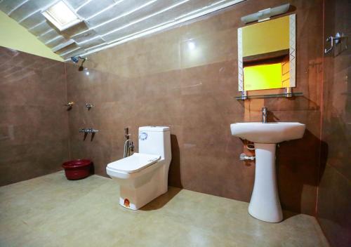 a bathroom with a sink and a toilet and a mirror at Chandragiri Wayanad Traditional Bungalow by VOYE HOMES in Vaduvanchal