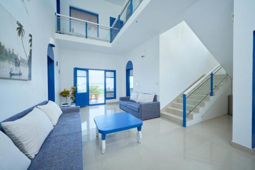a living room with a couch and a table and stairs at Seclude by the Lake, Alleppey in Alleppey