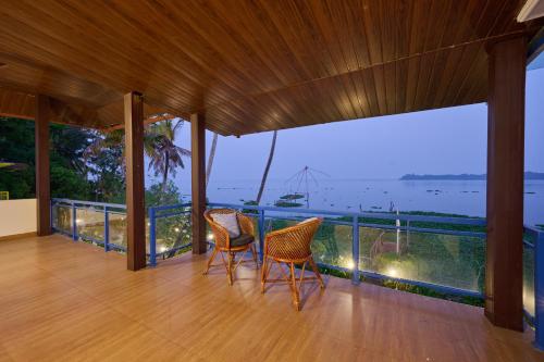 two chairs on a balcony with a view of the ocean at Seclude by the Lake, Alleppey in Alleppey