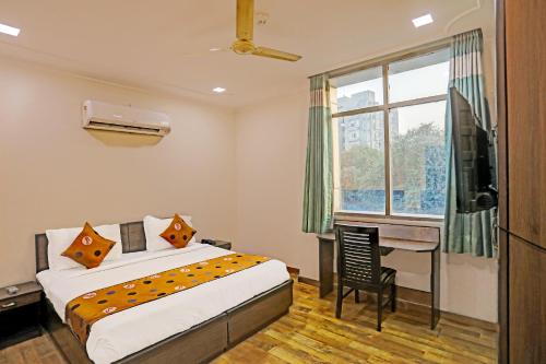 a bedroom with a bed and a desk and a window at Hotel Grand Tushar - Near Ghaziabad Railway Station in Ghaziabad