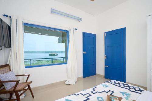 a bedroom with blue doors and a large window at Seclude by the Lake, Alleppey in Alleppey
