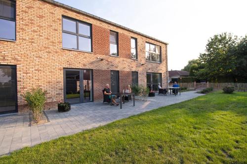 a brick building with people sitting at tables on a patio at De Hoog Velden 12 in Pelt