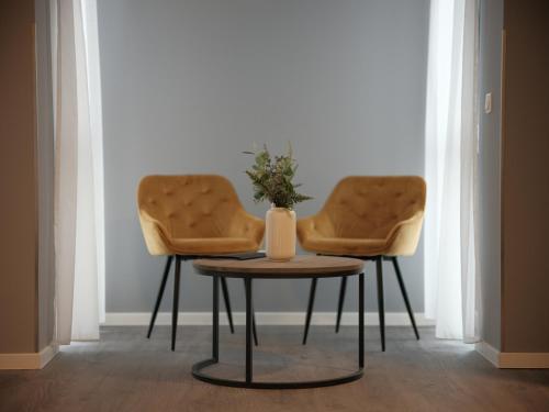 two chairs and a table with a vase on it at THE ROOMS - Hotel & House in Frankfurt